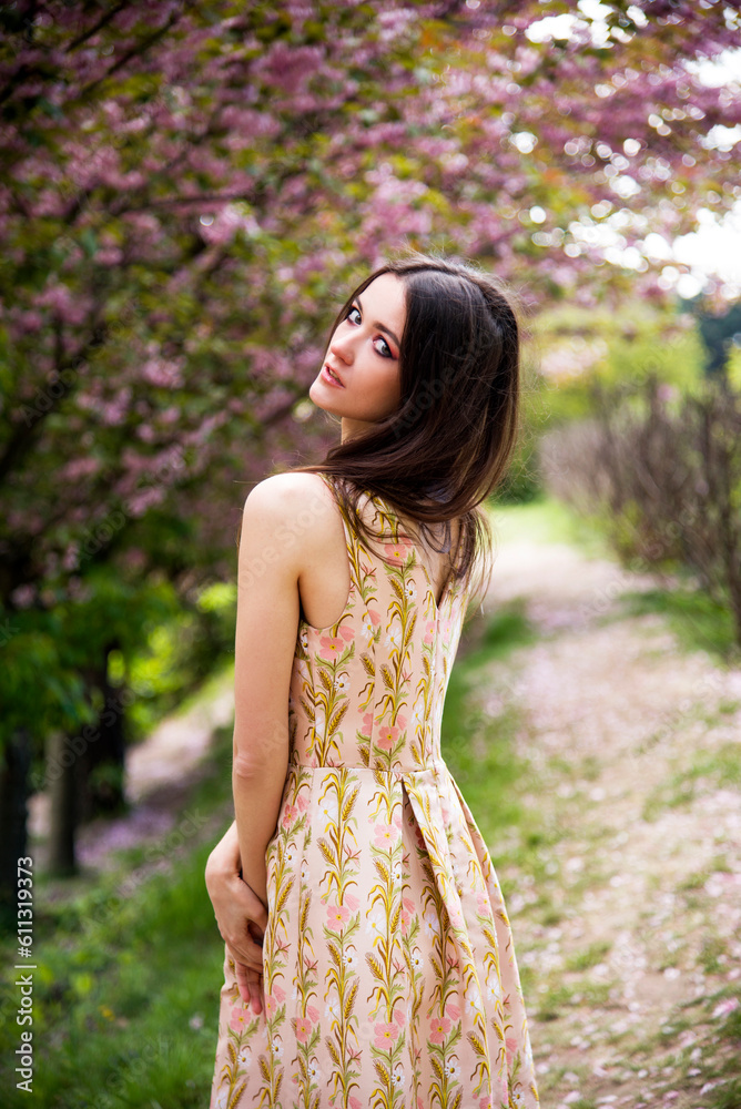 portrait of sensitive beautiful brunette woman with tattoo on her neck in dress in the garden near blossoming sakura flowers portrait of sensitive beautiful brunette woman with tattoo on her neck in dress in the garden near blossoming sakura flowers