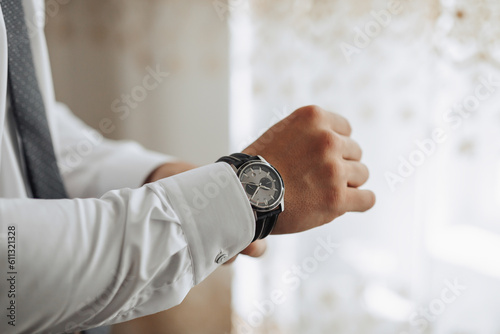 cropped photo of stylish man buttoning white shirt. Front view. A stylish watch. Men's style. Fashion. Business
