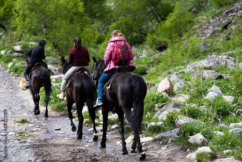 Horse riding. A group of people riding horses on a mountain trail. © eskstock