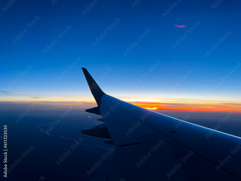 Plane wing over beautiful sunset at high altitude in dusk