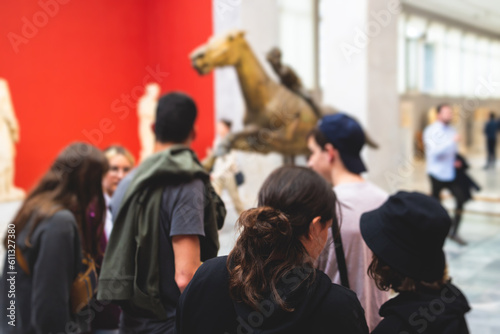 Group of students on excursion tour visit gallery museum with tour guide, a docent with a tourist adult visitors on an archaeology exhibition with contemporary art, hall with paintings and exhibits