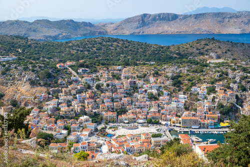 High and Breathtaking View of Colorful Houses and Port of Symi Below, the Blue Aegean Sea and the Mountains Beyond