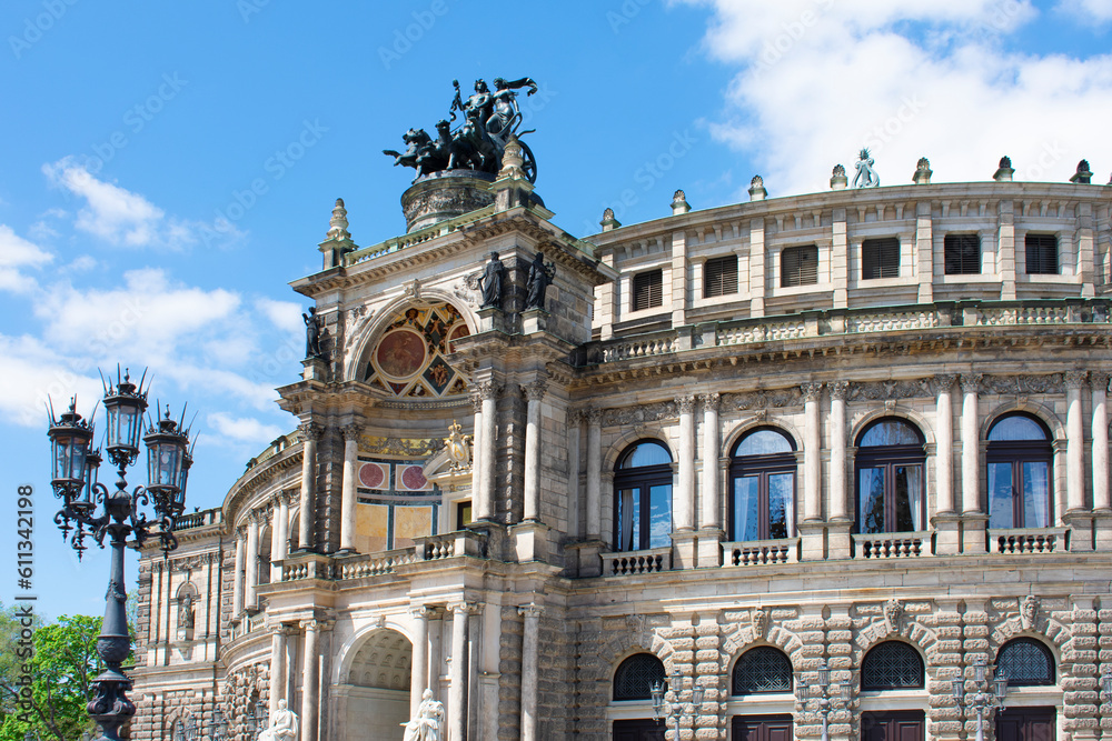 Fototapeta premium Facade of ancient architectural building with beige walls, statues, decorative elements, semicircular windows and lantern. Historical architecture. Old town. Opera House. Dresden, Germany, May 2023
