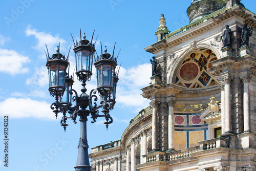 Facade of ancient architectural building with beige walls, statues, decorative elements and lantern. Historical architecture. Old town. Opera House. Sunny day, blue sky. Dresden, Germany, May 2023  © B.inna