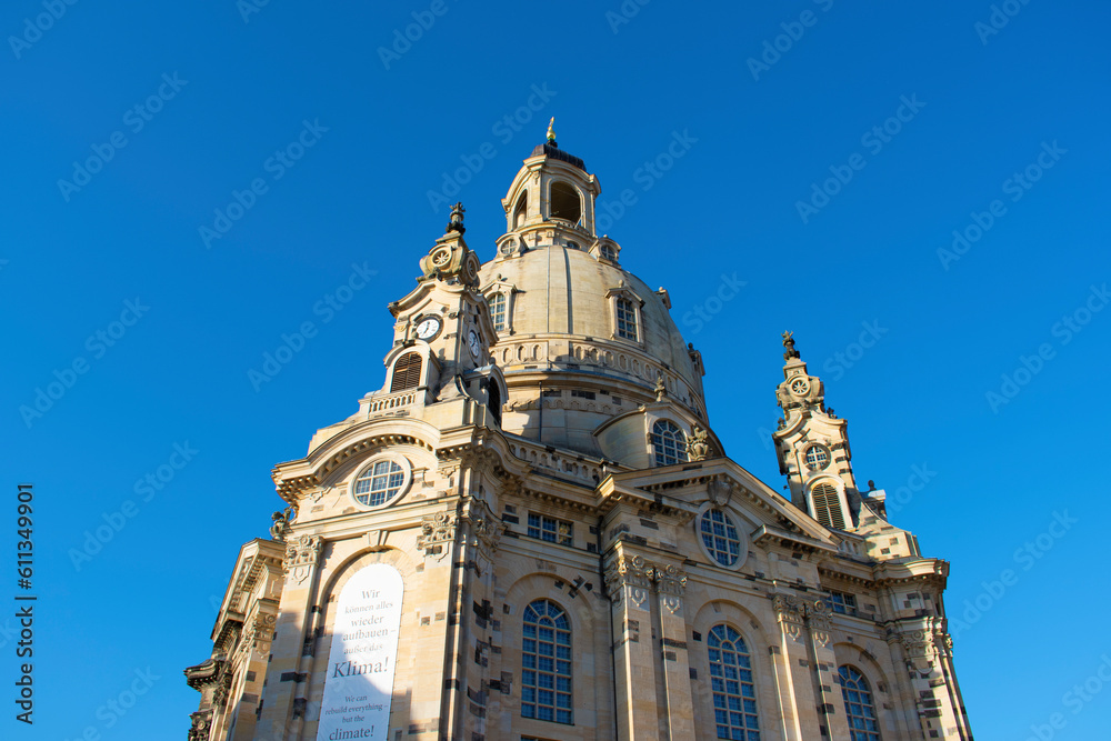 View of an old church with beige stone walls, dome, long semicircular windows and decorative elements on the facade. Frauenkirche. Old architecture. Sunny day with blue sky. Dresden, Germany, May 2023