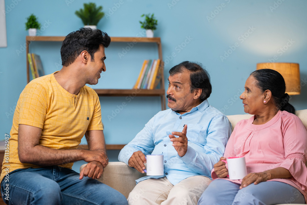 Indian happy adult son with senior parents talking or discussing together at home - concept of family communication, discussion and sharing thoughts. Indian happy adult son with senior parents talking or discussing together at home - concept of family communication, discussion and sharing thoughts.