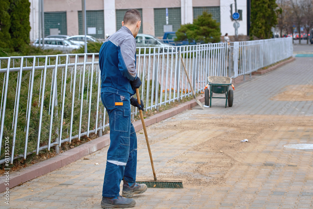 Worker with stiff brush grout and point paving slabs, paving industry