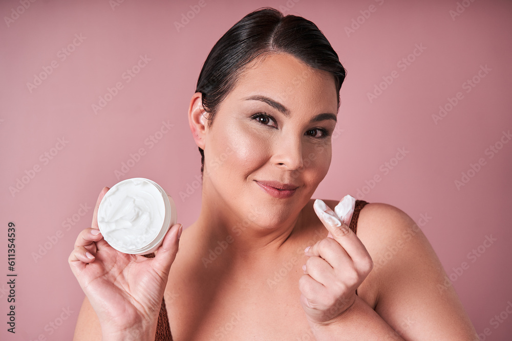 Happy body positive woman applying beauty product on her face and smiling