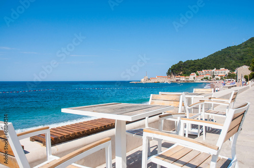 Cafe with wooden table and wooden chairs by the sea in Petrovac, Montenegro.