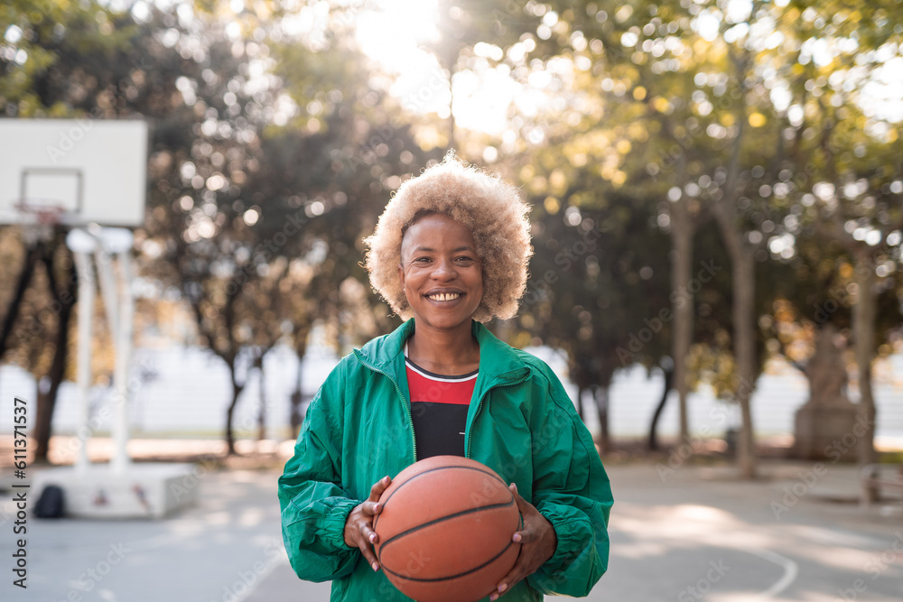 Positive young woman with basketball on court in park Positive young woman with basketball on court in park