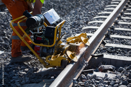 Unrecognizable worker cutting and leveling railway metal in daylight