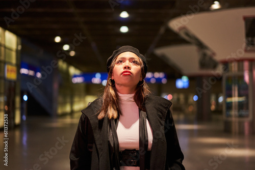 Young woman standing at international airport against timetable and looking