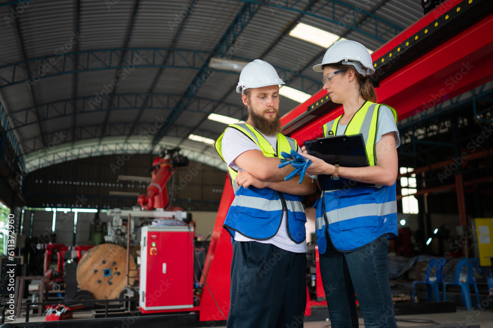 Both of engineers installing and testing a large robotic arm. before sending it to customers for use in the industry