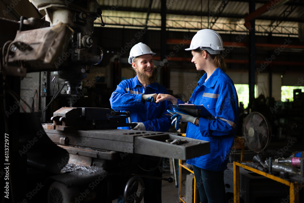 Both of mechanical engineers are checking the working condition of an old machine that has been used for some time. In a factory where natural light shines onto the workplace Both of mechanical engineers are checking the working condition of an old machine that has been used for some time. In a factory where natural light shines onto the workplace
