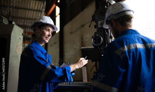 Both of mechanical engineers are checking the working condition of an old machine that has been used for some time. In a factory where natural light shines onto the workplace
