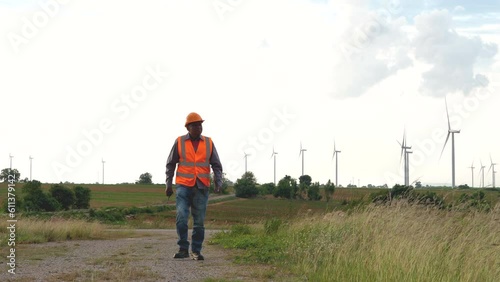 Senior engineer worker man walking in background wind turbines field, green environmental energy. windmill power station.