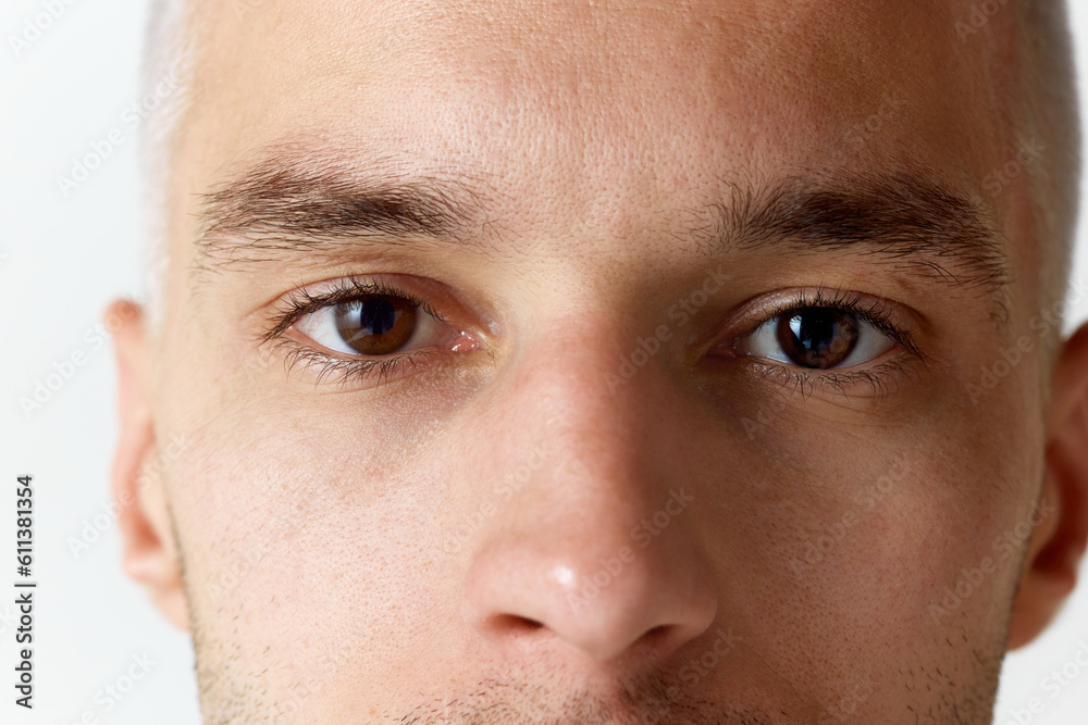 Cropped close-up image of man's face with brown eyes looking at camera against white studio background. Concept of men's beauty, skincare, cosmetology, spa, health. Copy space for ad Cropped close-up image of man's face with brown eyes looking at camera against white studio background. Concept of men's beauty, skincare, cosmetology, spa, health. Copy space for ad
