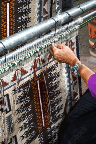 Cameron, Arizona: A Navajo woman demonstrates traditional rug weaving at the Cameron Trading Post,  a Native American cultural center.