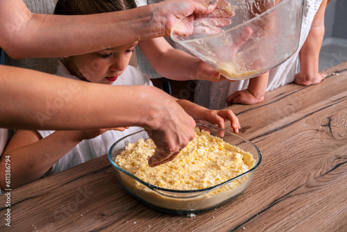 Close up female hands cooking pie. Little girl helps her mother to cook sweet cheesecake.