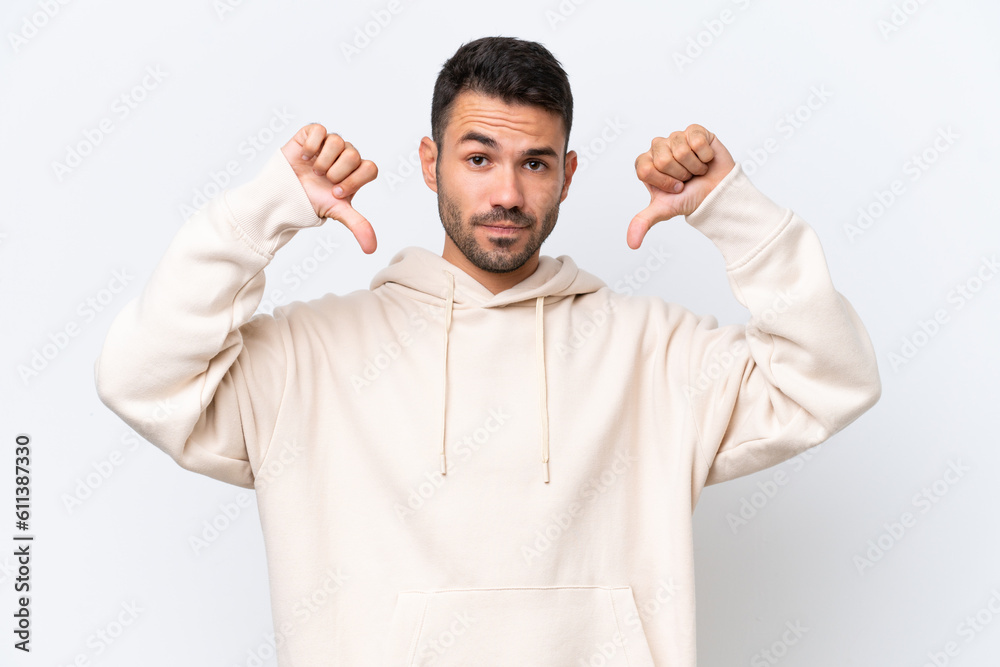 Young caucasian man isolated on white background showing thumb down with two hands Young caucasian man isolated on white background showing thumb down with two hands