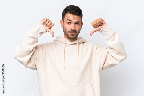 Young caucasian man isolated on white background showing thumb down with two hands © luismolinero