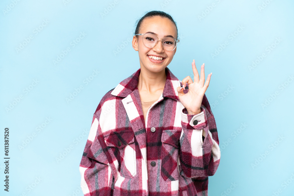 Young Arab woman isolated on blue background showing ok sign with fingers Young Arab woman isolated on blue background showing ok sign with fingers