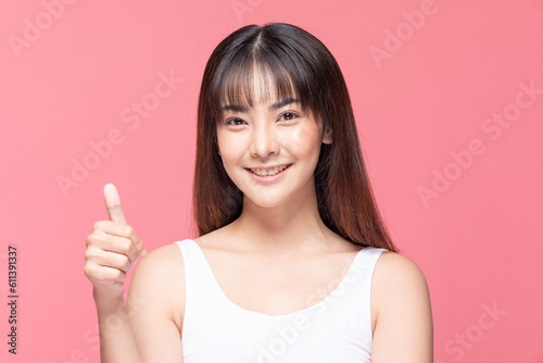 Beautiful Attractive Asian young woman smile and making good sign thumbs up feeling so happiness and confident Isolated on pink background Beauty Concept