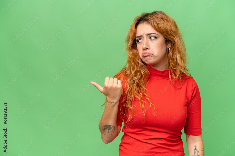 Young caucasian woman isolated on green screen chroma key background unhappy and pointing to the side Young caucasian woman isolated on green screen chroma key background unhappy and pointing to the side