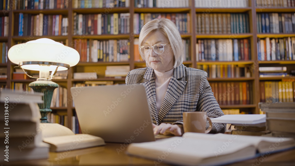 Woman working on her laptop late in the evening, a scientific researcher in the library Woman working on her laptop late in the evening, a scientific researcher in the library
