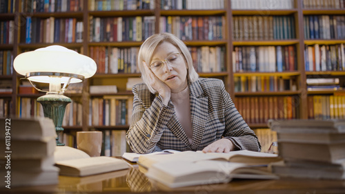 Exhausted woman scientist looking for information in books for a long time