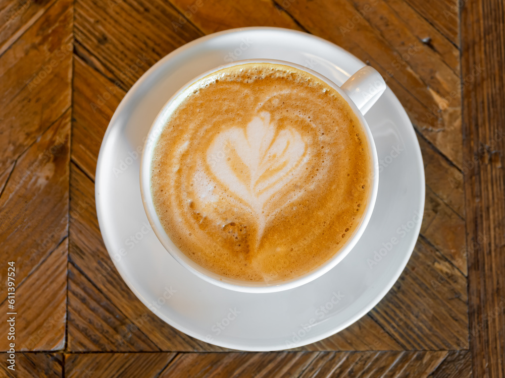 A cup of cappuccino with foam decoration on a wooden table A cup of cappuccino with foam decoration on a wooden table