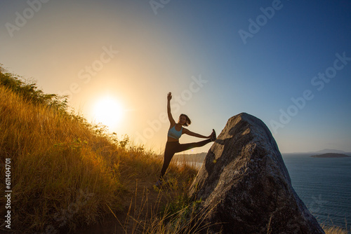 A lady stretching on the hilltop She was admiring the beautiful view of the sea below..She took a deep breath, savoring the moment of peace..On the top of the hill. fresh air