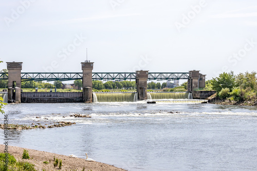 Water flowing in Borgharen dam and lock complex, waterworks to regulate river Maas, concrete pillar towers, steel gates in middle and working steel bridge on top, South Limburg in the Netherlands photo