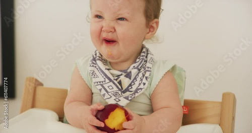 Baby, fruit and healthy eating at home for breakfast with sour and funny face from peach. Young child, food and nutrition of a kid in a high chair feeling hungry and tasting fruits in a house