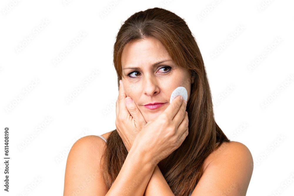 Middle age woman over isolated background with cotton pad for removing makeup from her face Middle age woman over isolated background with cotton pad for removing makeup from her face