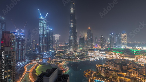 Skyscrapers rising above Dubai downtown all night timelapse surrounded by modern buildings aerial top view