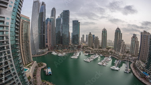 Dubai marina tallest skyscrapers and yachts in harbor aerial night to day timelapse.