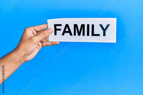 Hand of caucasian man holding paper with family word over isolated blue background