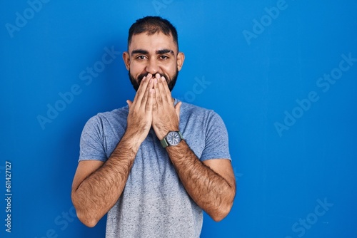 Принти на полотні Middle east man with beard standing over blue background laughing and embarrasse