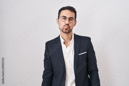 Handsome business hispanic man standing over white background looking at the camera blowing a kiss on air being lovely and sexy. love expression. © Krakenimages.com
