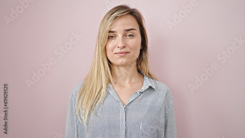 Young blonde woman standing with serious expression over isolated pink background © Krakenimages.com