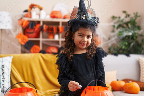 Adorable hispanic girl having halloween party holding sweet at home