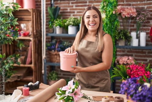 Young blonde woman working at florist shop smiling and laughing hard out loud because funny crazy joke.