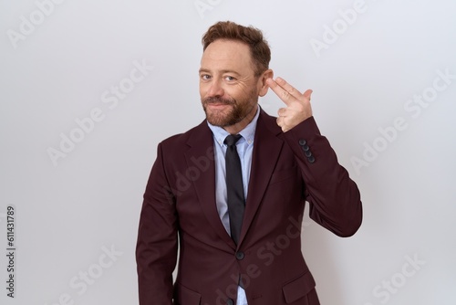 Obraz na plátne Middle age business man with beard wearing suit and tie shooting and killing oneself pointing hand and fingers to head like gun, suicide gesture