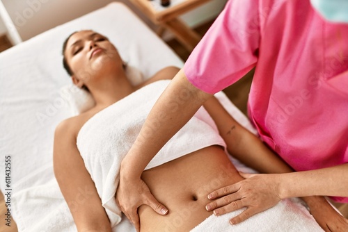 Young beautiful hispanic woman lying on table having massage at beauty salon