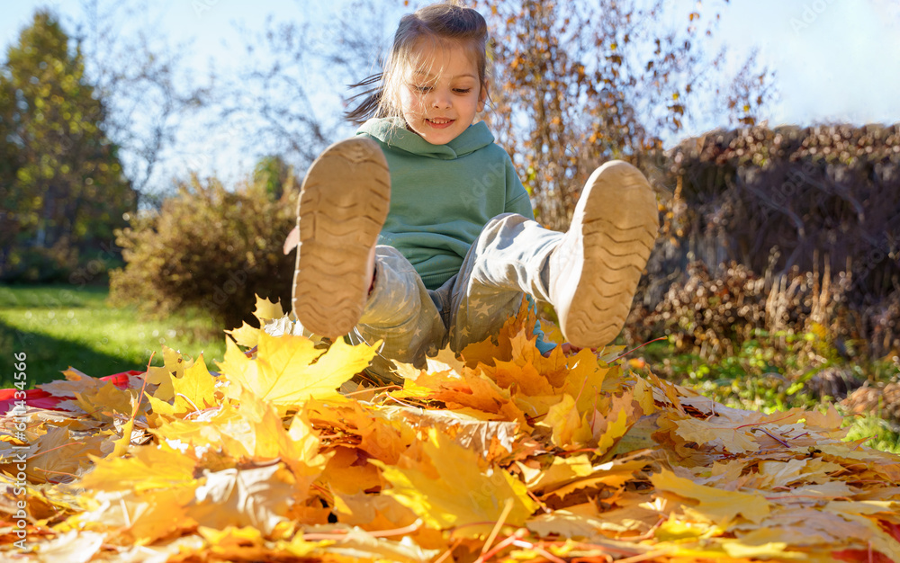 Girl kid jumping on trampoline with autumn leaves. Bright yellow orange