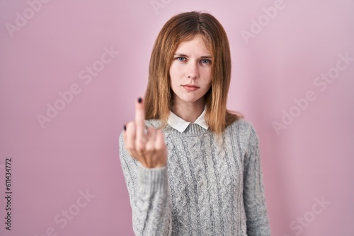 Beautiful woman standing over pink background showing middle finger, impolite and rude fuck off expression