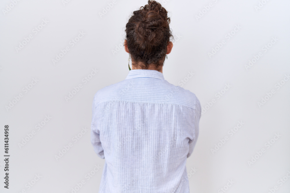 Hispanic man with beard wearing casual shirt standing backwards looking away with crossed arms Hispanic man with beard wearing casual shirt standing backwards looking away with crossed arms
