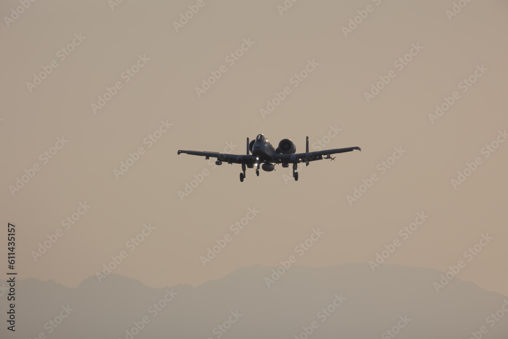 Fighter jet in silhouette over an evening sky with a mountain backgroud