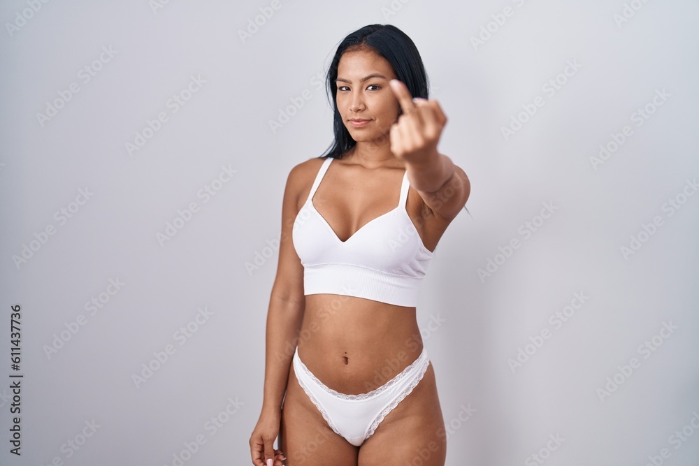 Hispanic woman wearing lingerie showing middle finger, impolite and rude fuck off expression Hispanic woman wearing lingerie showing middle finger, impolite and rude fuck off expression